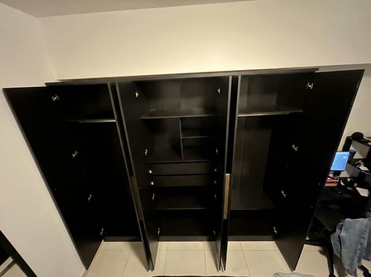 Interior do guarda-roupa com as portas abertas e vazio, mostrando as prateleiras, os cabideiros e as gavetas.