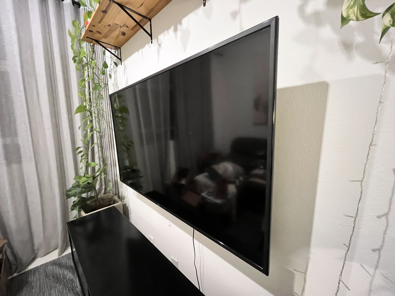 TV LG de tela plana instalada na parede, vista em ângulo, mostrando a moldura fina e a espessura do aparelho.