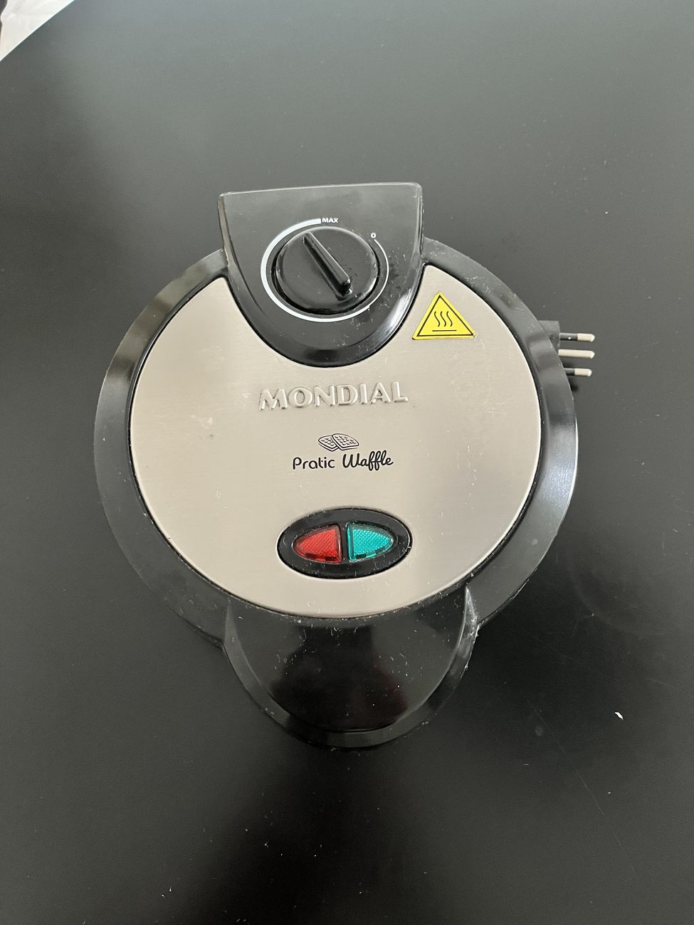 A máquina de waffle fechada, vista de cima, com a marca Mondial Pratic Waffle e o termostato.