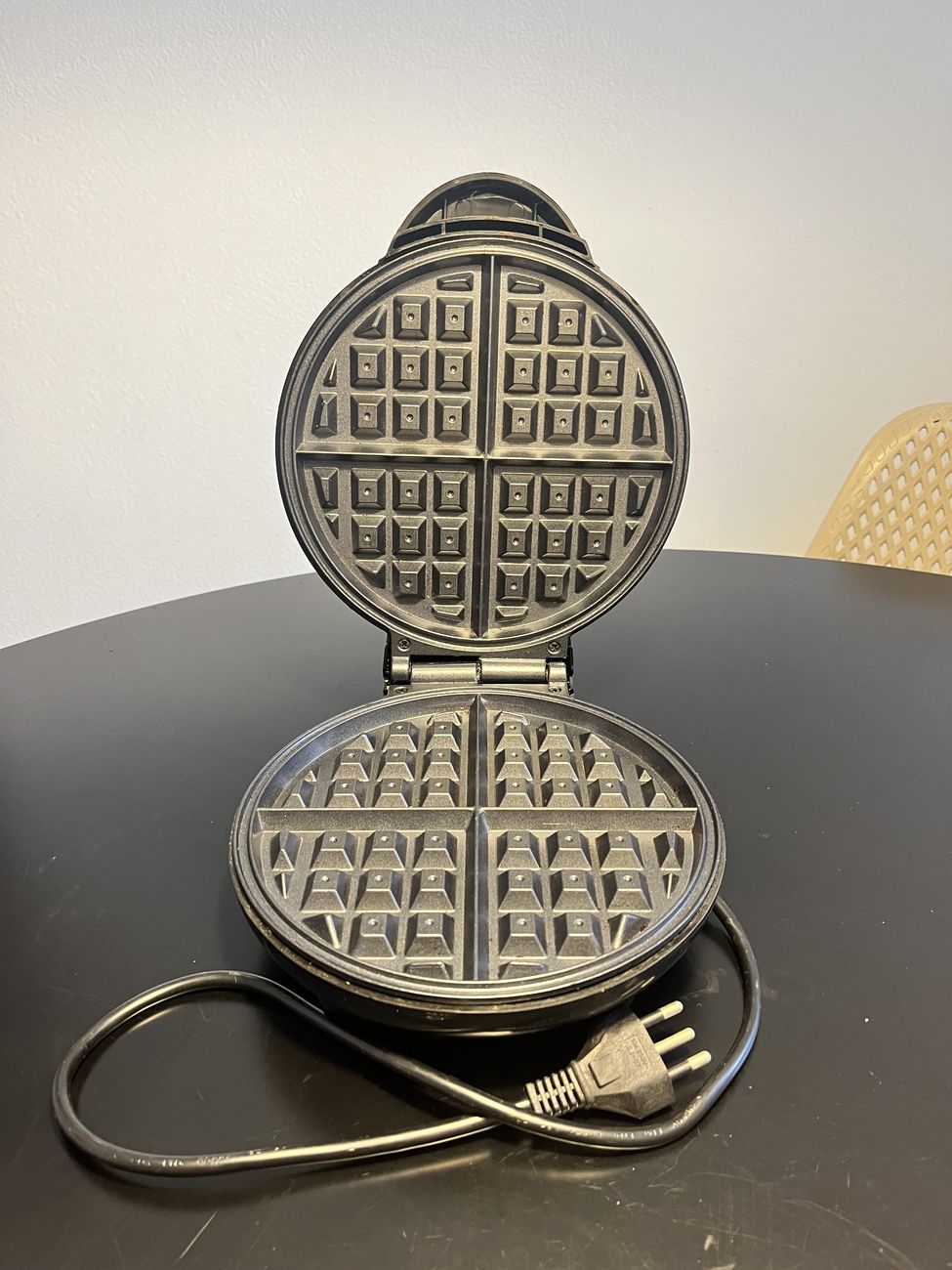 Máquina de waffle aberta, mostrando as duas chapas redondas com o desenho quadriculado.