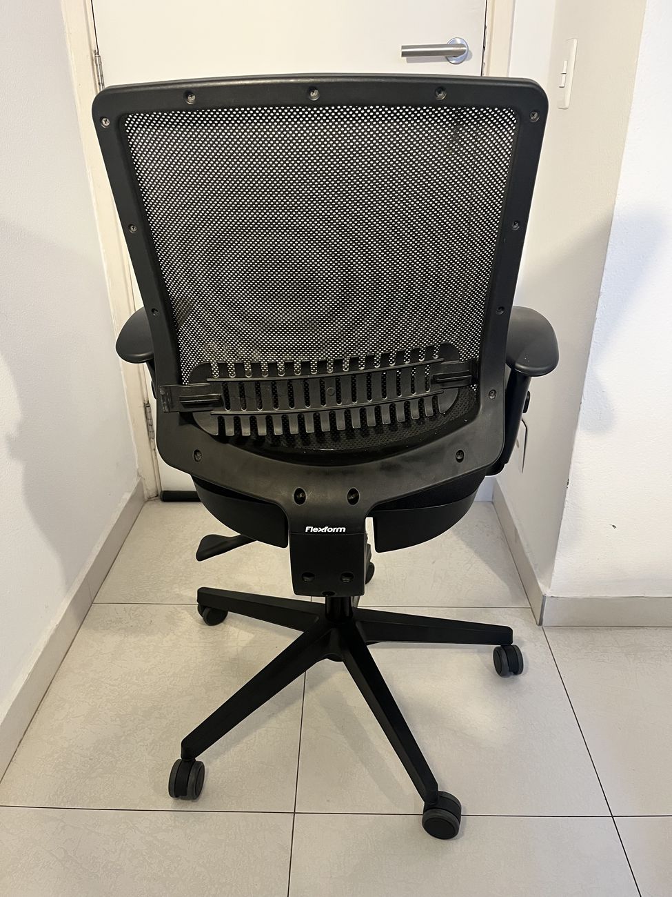 Traseira da cadeira, com a marca Flexform na base do encosto.